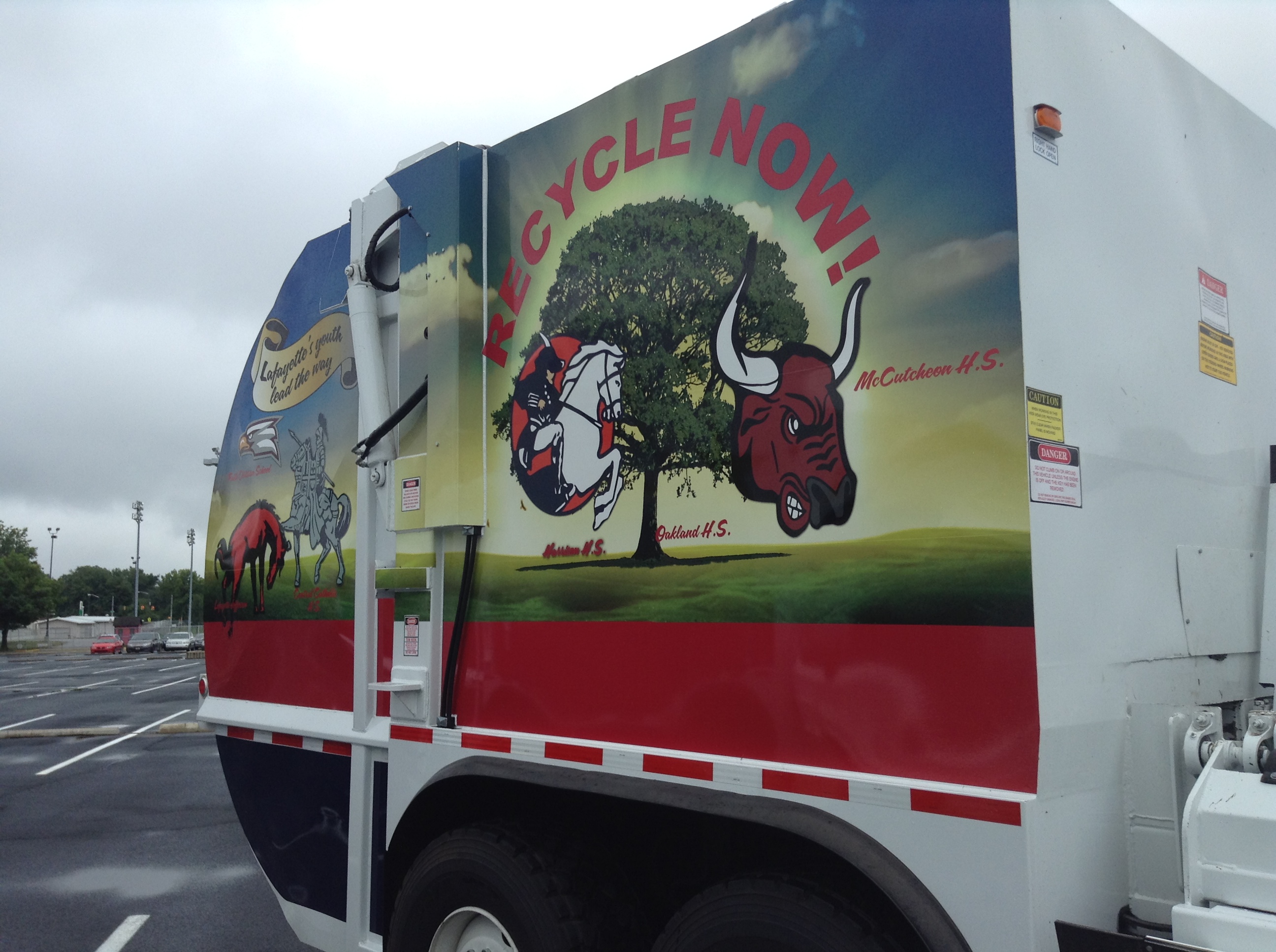 A trash truck with a bull and a tree on the side